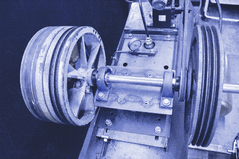 Image: Solid steel shaft with three compressor pulleys used as flywheels. Photo by Andy Lagzdins.